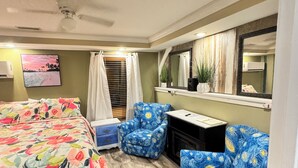 A bedroom with a bed, two chairs, a desk, a mirror, a ceiling fan, and a painting on the wall. -  Amazing Suite w Fireplace & Washer & Dryer! Pets & 420 Friendly (Gatlinburg)