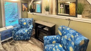 A room with two blue armchairs, a small table, and a mirror above a window. -  Amazing Suite w Fireplace & Washer & Dryer! Pets & 420 Friendly (Gatlinburg)