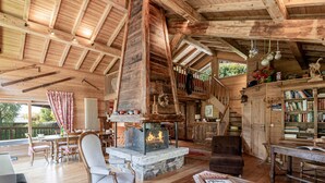 A rustic cabin interior with a stone fireplace, wooden furniture, and a bookshelf. - Typical Chalet in Chamonix with Parking and Wifi, Near Center and Slopes (Chamonix-Mont-Blanc)