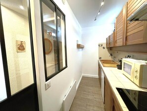 Une cuisine de taille réduite, équipée d’un four à micro-ondes, d’un évier et de meubles de rangement en bois.