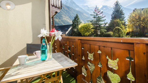 A wooden balcony with a table, a white mug, and a bottle of water. - Lovely apartment in Chamonix center, near slopes with parking (Chamonix-Mont-Blanc)