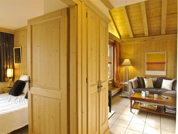 Een kamer met een bed, een houten garderobe, een bank, een salontafel en een lamp.