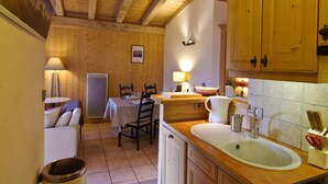 Une cuisine chaleureuse avec des meubles de rangement en bois, un évier et un coin repas comprenant une table et des chaises.