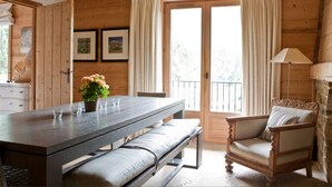 Een houten hutje met een eettafel, een bank en een stoel.