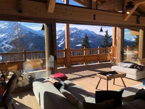 Ein Holzinnenraum mit einem Balkon mit Blick auf schneebedeckte Berge.