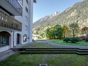 A building with a courtyard, steps leading to a door, and a view of a mountain.