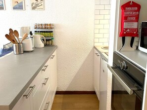 A kitchen with a toaster, a kettle, and a spice rack.