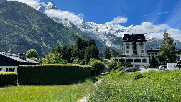 Eine Berglandschaft mit schneebedeckten Gipfeln, blauem Himmel und einem Gebäude mit zahlreichen Fenstern und Balkonen.