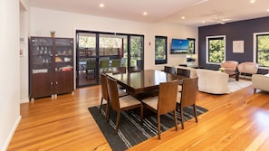 Relax in this spacious living area with a dining table, sofa, and armchairs, surrounded by a large window with a view of the outdoors.