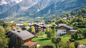 A mountainous landscape with a village featuring traditional wooden houses and a prominent mountain peak in the background.