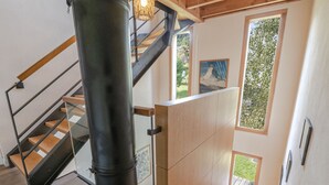 A staircase with a glass railing, a wooden door, and a view of greenery outside.