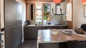 A modern kitchen with wooden beams, a central island, and a window with a view of greenery.