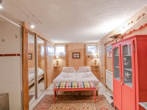 A cozy bedroom with a bed, a bench, and a red cabinet. - Beautiful duplex with garden in Chamonix, 4 people, pets allowed, parking, wifi (Chamonix-Mont-Blanc)