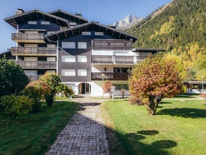 A multi-story hotel with balconies, a paved driveway, and a mountainous backdrop.