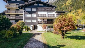 A multi-story hotel with balconies, a paved pathway, and a mountainous backdrop.