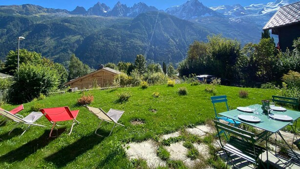 Vista de la montaña con comedor, que incluye mesas y sillas, y un edificio de madera.