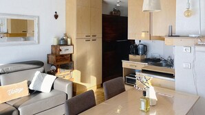Um espaço de estar compacto com sofá, mesa de jantar e cozinha compacta.
