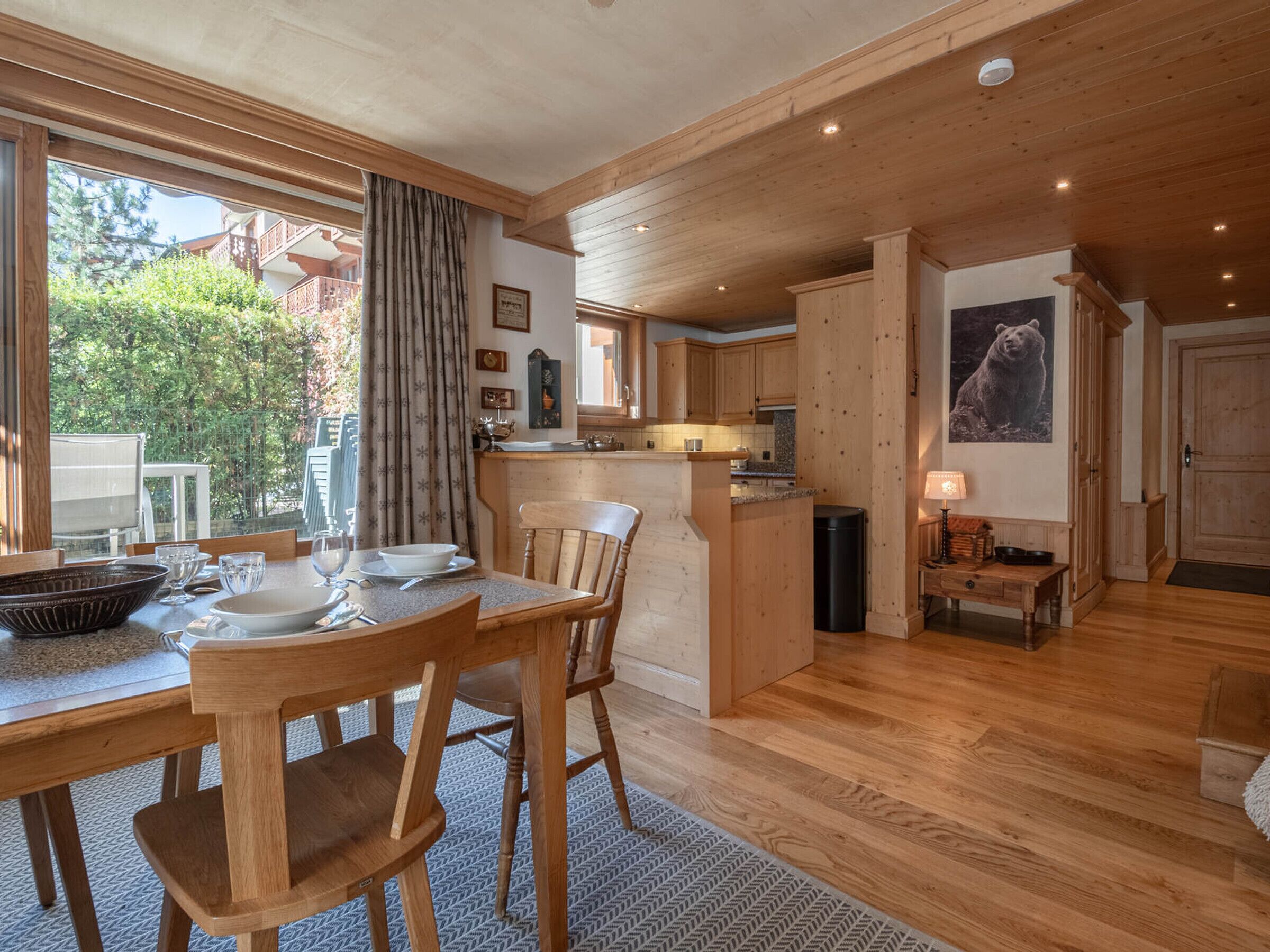 A spacious kitchen with wooden cabinets, a dining area with a table and chairs, and a view of the outdoors through large windows.