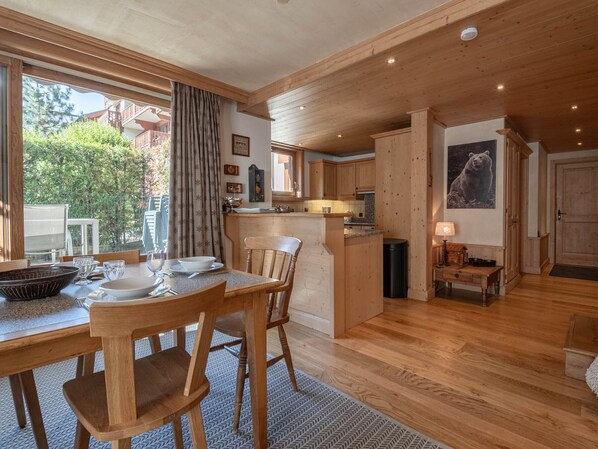 A spacious kitchen with wooden cabinets, a dining area with a table and chairs, and a view of the outdoors through large windows.