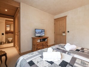 A bedroom with a bed, a wooden wardrobe, a television, and a bathroom visible through an open door. - Spacious 6-room apartment for 10 near slopes, pets OK, parking, WiFi (Chamonix-Mont-Blanc)