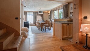 A spacious living area with wooden floors, a dining table, and a kitchen area with wooden cabinets. - Spacious 6-room apartment for 10 near slopes, pets OK, parking, WiFi (Chamonix-Mont-Blanc)