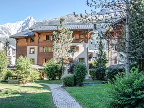 A multi-story building with a wooden facade, a brick pathway, and a mountainous backdrop. - Spacious 6-room apartment for 10 near slopes, pets OK, parking, WiFi (Chamonix-Mont-Blanc)