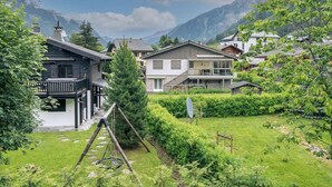 Un quartier résidentiel avec des maisons, une balançoire et une chaîne de montagnes en arrière-plan.