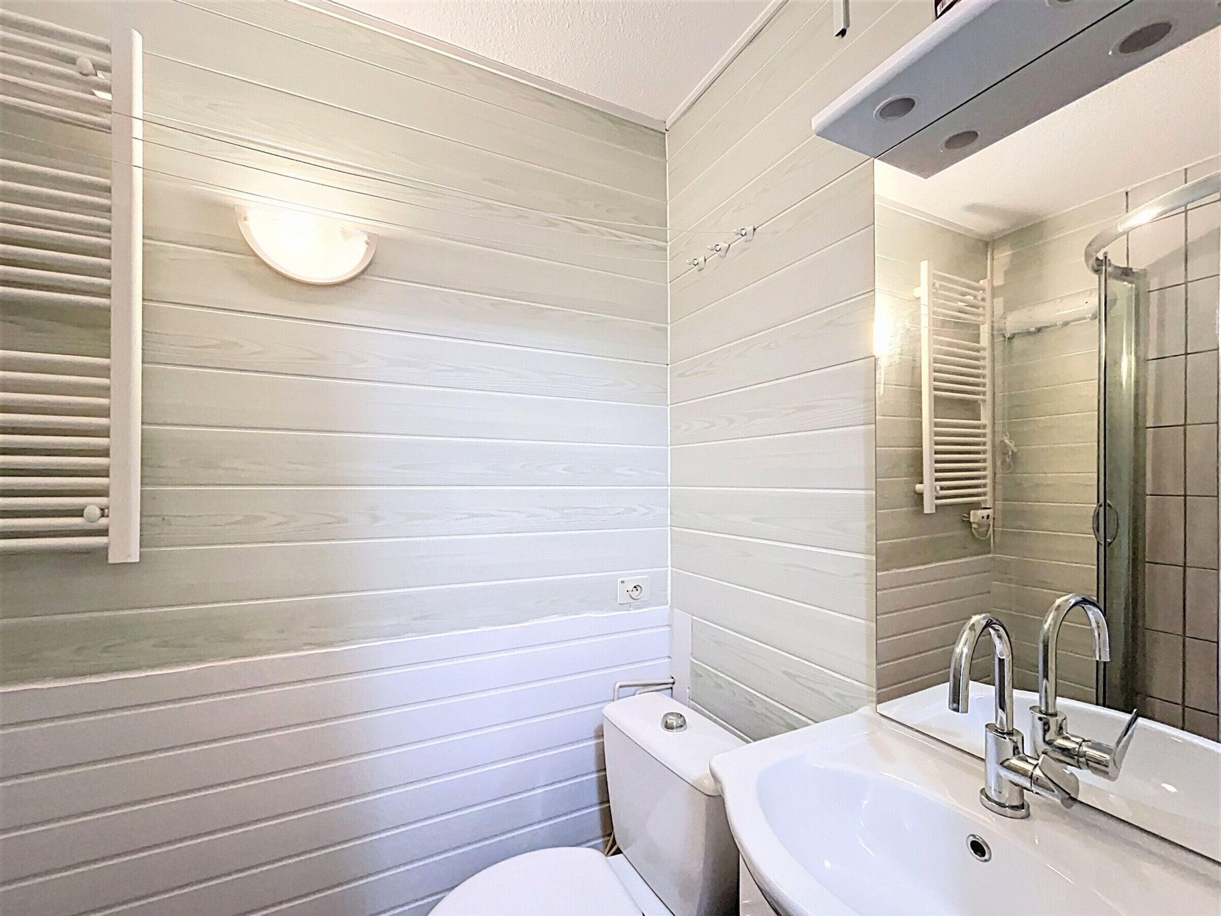 Ein Badezimmer mit Toilette, Waschbecken mit Spiegel und Handtuchhalter.