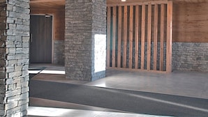 A spacious interior with stone pillars, wooden beams, and recessed lighting. - Renovated Duplex - Sleeps 6 - Ski-in/Ski-out - Mountain View Balcony - Close to Shops (Val Thorens)