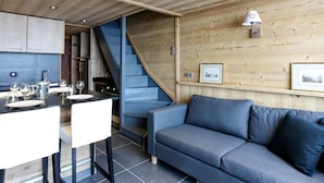 A modern kitchen with a dining area, a sofa, and a staircase. - Renovated Duplex - Sleeps 6 - Ski-in/Ski-out - Mountain View Balcony - Close to Shops (Val Thorens)