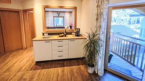 Eine moderne Küche mit Holzschränken, einem Einbauofen und einem großen Fenster mit Blick auf einen Balkon.