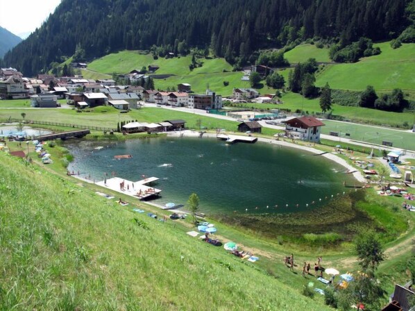 A lakeside village with a central pond, surrounded by houses and a small dock. - Apart M&M by Interhome (See)
