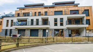 Een modern, meerlaags gebouw met een houten gevel, balkons en een bord met 'Biotop Immobilien'.