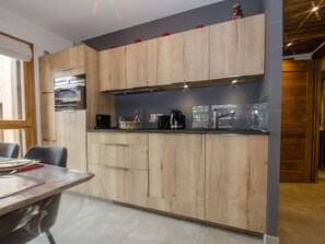 A modern kitchen with wooden cabinets, a black countertop, and a dining area with a table and chairs.