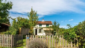 A white house with a red roof, surrounded by a wooden fence and lush greenery. - Le Glaude by Interhome (Chiddes)