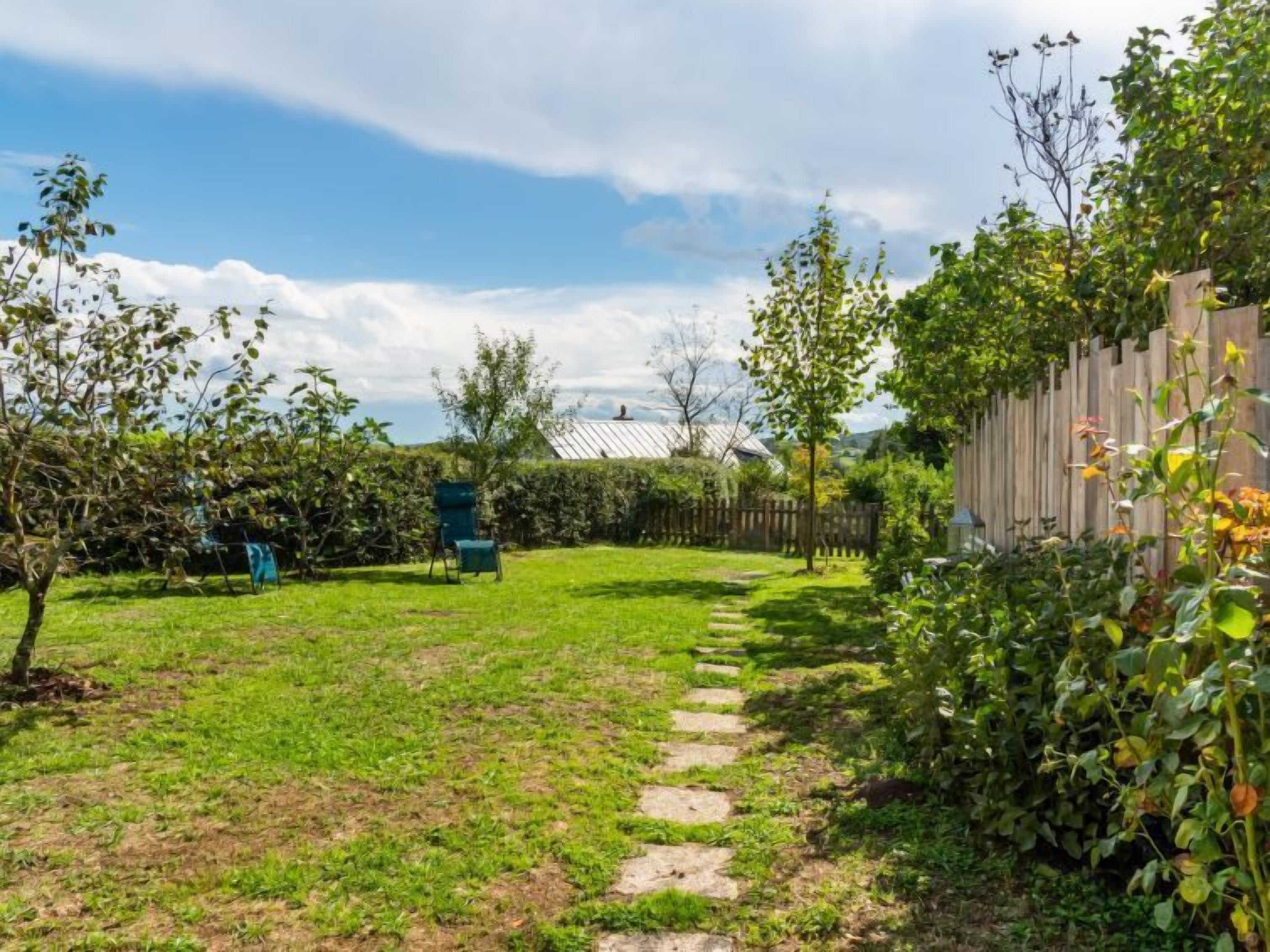 Ein Garten mit Holzpforte, einem Weg und einem Stuhl.