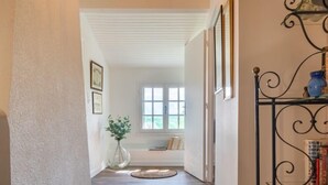 A hallway with a wooden floor, a white door, and a window with blinds. - Le Glaude by Interhome (Chiddes)