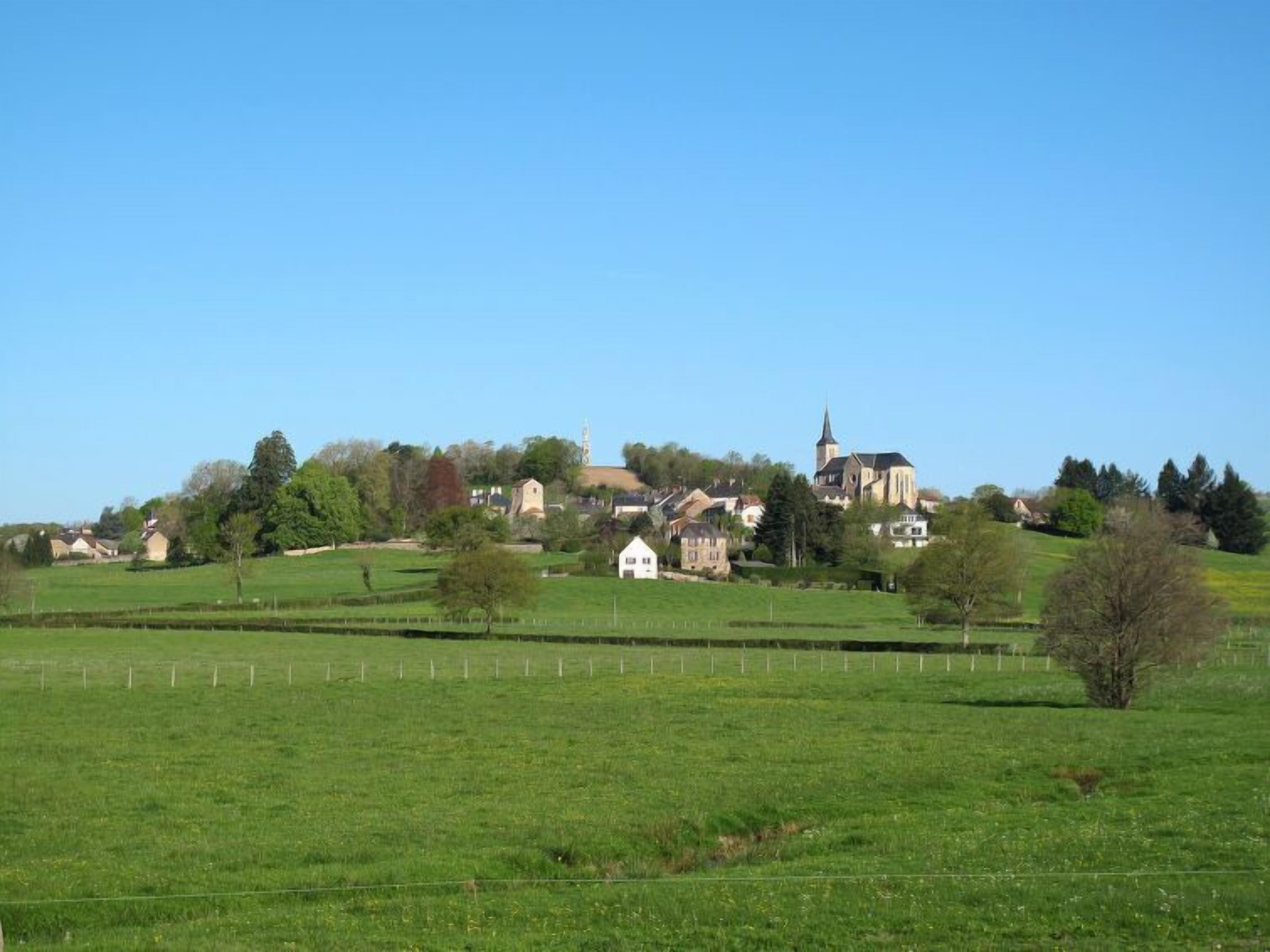 A rural landscape with a church, houses, and open fields.