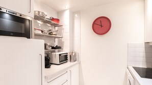 A modern kitchen with white cabinetry, a stainless steel refrigerator, a microwave, and a red clock on the wall. - Bright apartment for 5, Chamonix center, parking included (Chamonix-Mont-Blanc)