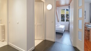 A hallway leading to a bedroom with a bed, a window with a view of the outside, and a dining area with a table and chairs. - Bright apartment for 5, Chamonix center, parking included (Chamonix-Mont-Blanc)