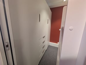 Ein schmaler Flur mit einer Tür links und einer roten Wand rechts.