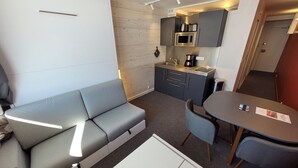 Un espacio habitable compacto con sofá, mesa de comedor y kitchenette.