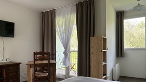 Une chambre à coucher comprenant un lit, un bureau, une chaise, une armoire et un téléviseur.