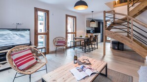 A modern living room with a wooden staircase, a dining area, and a kitchen. - 3-star duplex for 6 pers, Chamonix, private parking (Chamonix-Mont-Blanc)
