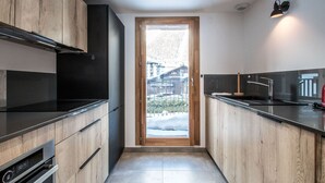 A modern kitchen with wooden cabinets, a black countertop, and a built-in oven. - 3-star duplex for 6 pers, Chamonix, private parking (Chamonix-Mont-Blanc)