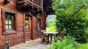 Una cabana de fusta amb un porxo, una taula i caires, i una decoració de cap de cérvol.