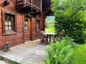 A wooden cabin with a porch, a table with chairs, and a deer head decoration. - Charming mazot with garden, pets allowed, parking, wifi (Chamonix-Mont-Blanc)