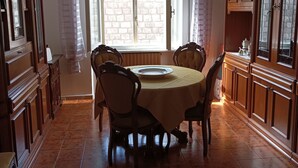 A dining area with a round table, chairs, a chandelier, and wooden cabinets.