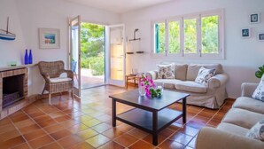 A living room with a fireplace, a sofa, a coffee table, and a view of the outdoors. - Murada Lisboa by Interhome (Cala Murada)