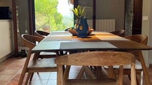 Ein Essbereich mit Holztisch und -stühlen, einer Pendelleuchte und Blick auf Grünflächen.